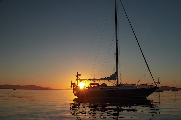 Sailboat Silhouetted Against the Sunset by Pacific Northwest Sailing Sailboat Silhouetted Against the Sunset by Pacific Northwest Sailing